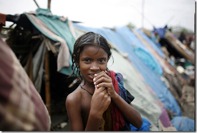 A girl displaced from her home by a huge tidal wave caused by Cyclone Aila, stands in front of her temporary shelter on a river dam in Satkhira in southwestern Bangladesh June 2, 2009. (REUTERS/Andrew Biraj) #