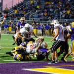 Matt Stone twists for a touchdown while teammates celebrate the moment.