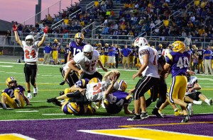 Matt Stone twists for a touchdown while teammates celebrate the moment.